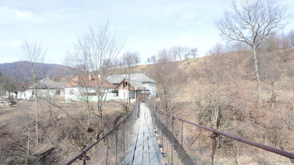old pedestrian suspension bridge over a mountain river of metal bars and wooden floor