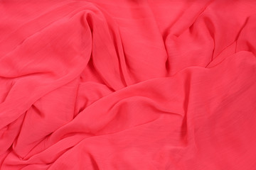 Background from satin fabric of coral color with waves.