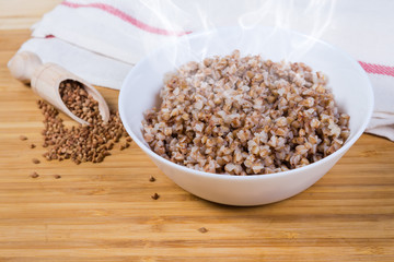Freshly prepared buckwheat porridge against the uncooked buckwheat groat