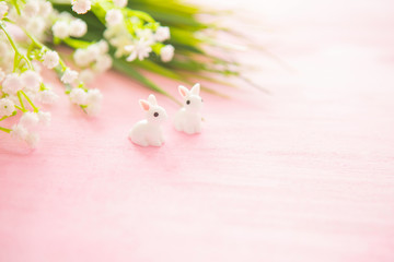 Easter bunny statuettes and flowers on wooden background