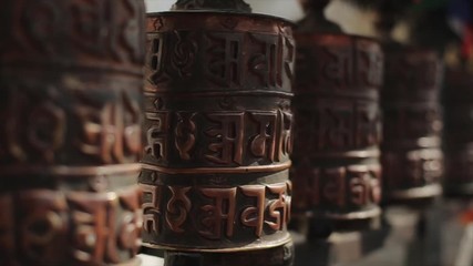 A close-up of a spinning buddhist prayer wheel in a row of wheels in Nepal Kathmandu