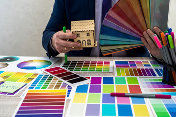 graphic or interior young designer in suit choosing color from swatch sample or catalogue palette...