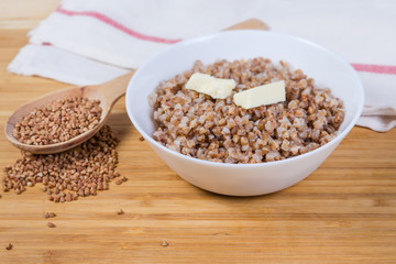 Buckwheat porridge with butter and uncooked buckwheat groat, close-up
