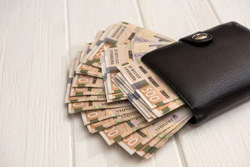 UAH, Black men's wallet is full of money. UAH Money of Ukraine 1000 and 500 banknotes on desk