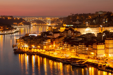 Barrio de La Ribeira de Oporto, río Duero y puente de la Arrábida iluminados al atardecer desde Vila Nova de Gaia (Portugal). - obrazy, fototapety, plakaty
