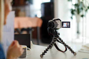 Young business woman recording video for her vlog shows papers with graphs to the cameras in focus