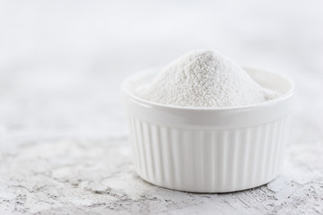 Rice flour in a bowl on a gray background. Gluten free, healthy diet concept. Horizontal orientation, copy space.