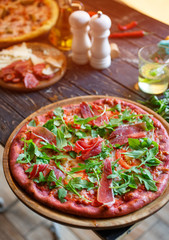 Pizza with ham, tomatoes, spices and fresh arugula. Italian pizza.