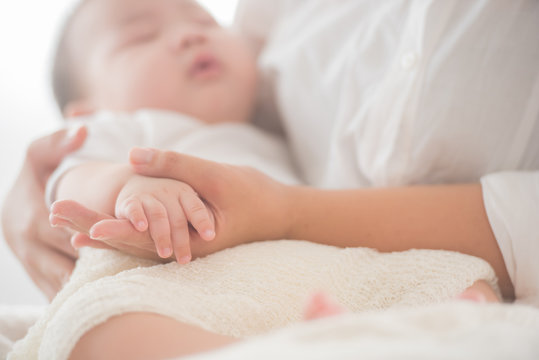 newborn baby hand while the mother is carrying in home. baby hand in mother hands. mom and her child. happy family concept. beautiful conceptual image of maternity. soft focus of baby hands and mom.
