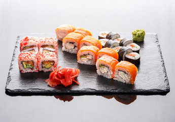Different types of sushi rolls on a stone board.