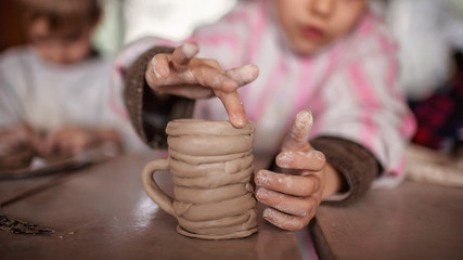 Cute little kids playing together with modeling clay in pottery workshop, craft and clay art - obrazy, fototapety, plakaty