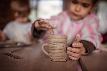 Cute little kids playing together with modeling clay in pottery workshop, craft and clay art