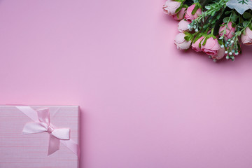Gift box with pink bouquet of roses on powder pink paper background. Flat lay.