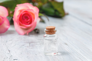 Pink roses, oil bottles and candles on a gray wooden table. March 8. Valentine's Day. Greeting card. Romantic and beautiful background. Spa treatments. Personal care. Love and beauty.