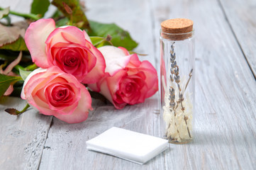 Pink roses, oil bottles and candles on a gray wooden table. March 8. Valentine's Day. Greeting card. Romantic and beautiful background. Spa treatments. Personal care. Love and beauty.