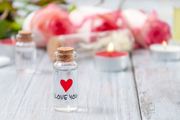 Pink roses, oil bottles and burning candles on a gray wooden table. March 8. Valentine's Day. Greeting card. Romantic and beautiful background. Spa treatments. Personal care. Love and beauty.