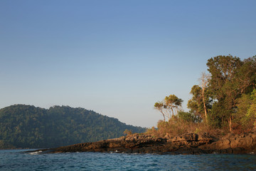 Fototapeta na wymiar rock shore protruding into the sea. Seascape caught by soft morning cool warm light. Tip of a land cape poising in the ocean. Dream vacation destination Thailand.