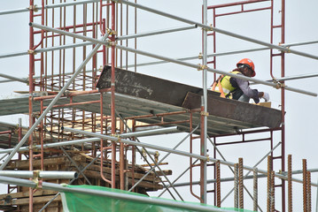 Fototapeta premium Construction workers wearing safety harness and installing scaffolding at high level in the construction site.