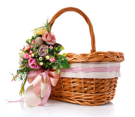 Fototapeta na wymiar Brown wicker basket with original handle. Decor with flowers, eggs and ribbons. Isolated on a white background.