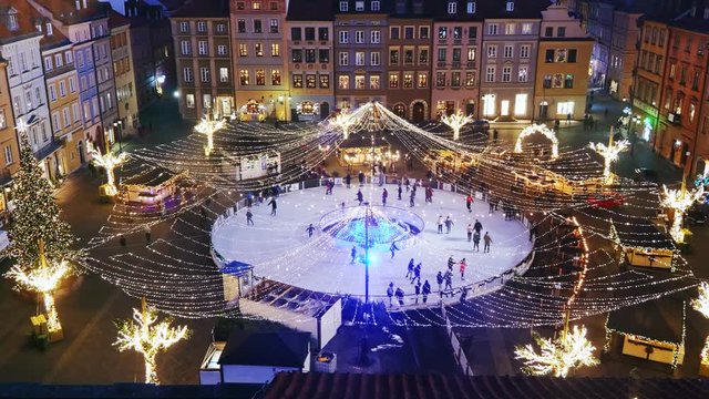City of Warsaw in Poland, people having fun on ice skating rink on Old Town square at night, Christmas season holiday city break.