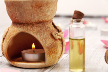 Obraz na płótnie Canvas Aroma lamp with a burning candle and essential oils, pink salt bath bomb in the form of a heart, rose petals on a gray wooden table. Face and body care. Spa treatments.
