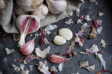 Garlic in burlap. Peeled garlic cloves, garlic bulb on a dark background. Healthy eating concept.
