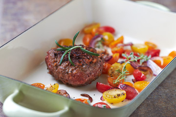 Hamburger steak with cherry tomatoes and fresh herbs.