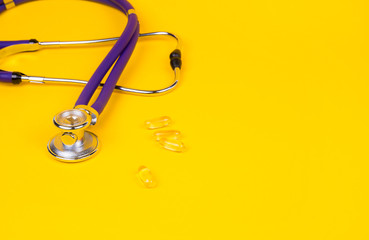 Medical stethoscope and pills on contrast yellow background. Place for text. Medication...