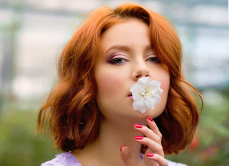 beautiful red-haired girl in arranger where azalea blooms in a colorful flying dress