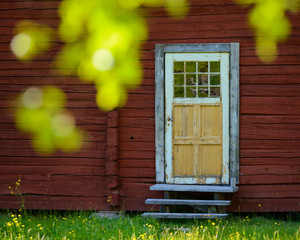 Farm door behind green foliage. Dalarna, Sweden.