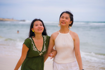 young beautiful and happy couple of attractive Asian Chinese women walking together relaxed at the beach enjoying holidays having fun feeling free and joyful