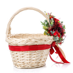 Fototapeta na wymiar Floral decor on the handle of a wicker basket. Decor with bright red flowers, greenery, and ribbons.