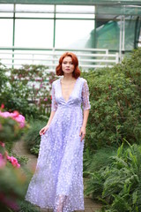 beautiful red-haired girl in arranger where azalea blooms in a colorful flying dress