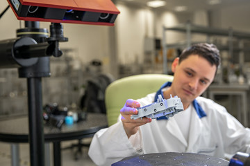 Quality engineer examines a sample scanned with a laser on a 3d scan in a research laboratory