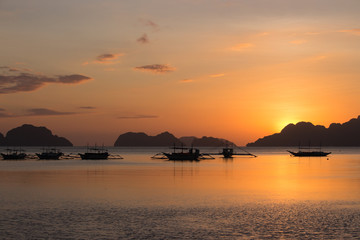 Beautiful calm sunset in Philippines, Palawan. Boats at sea with islands and mountains on horizon. Evening dusk at the sea. Evening seascape panorama. Tropical lagoon. Bright colors of sunset.