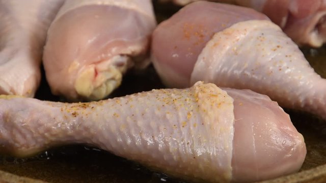 Chicken legs sprinkled with spices in a pan