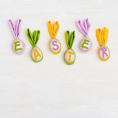 Easter composition with handmade easter eggs with ears from rabbit and word 