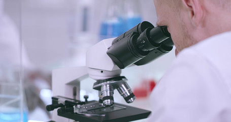 Close-up of a microscope and a working man