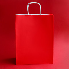 Red paper bag with handles closeup shopping background