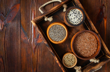 Superfoods, healthy food supplements. Chia, flax, sesame and hemp seeds, save space, top view on wooden background.