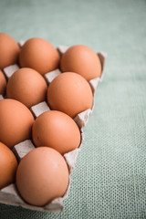 Hen eggs in paper carton box on background table. Organic products from farm. Copy space. Breakfast menu concept. 