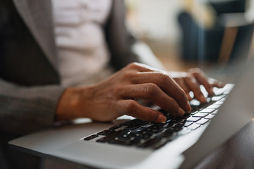 Close-up of black businesswoman working on laptop.