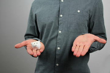 Fototapeta premium man in a gray shirt holds a small white piggy bank in his hand, the other palm is empty, the concept of savings and alternatives, close-up