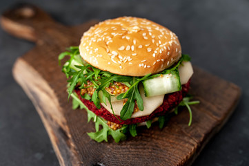  veggie burger with beets, chickpeas, pear, arugula, cucumber on a cutting board on a stone background