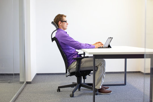 Correct Sitting Position At The Office Desk . Man On Chair Working With Tablet