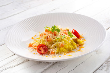 Smoked cheese risotto and salted salmon on white wood background.