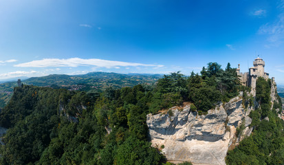 Aerial view on medieval fortress on top of the mountain, fortifications, in the background mountains and the city. The concept of the best places for tourism and holidays in Europe. San Marino, Italy