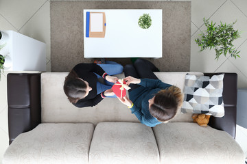 Two lesbian woman sit at sofa and present gift closeup top view bacground