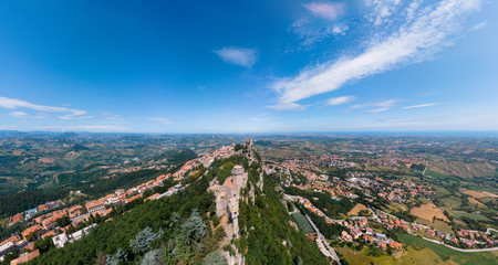 Aerial view on medieval fortress on top of the mountain, fortifications, in the background mountains and the city. The concept of the best places for tourism and holidays in Europe. San Marino, Italy