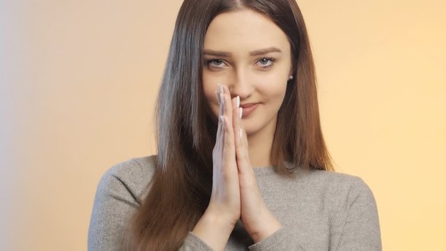 beautiful cute girl moves her fingers while waiting on a pastel studio color background, the face of a young woman with makeup, the concept of female mood and emotions